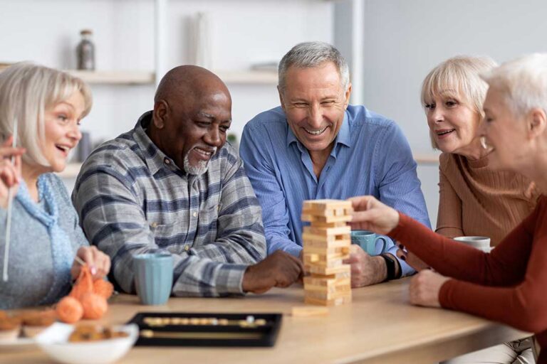 Older resident and family member review end-of-life care documents with a caregiver at a bedside table.