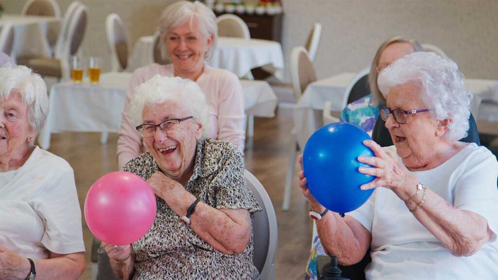 An older adult and family member unpacking boxes together in a cozy, sunlit assisted living apartment.
