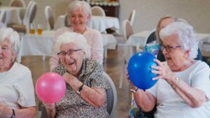 An older adult and family member unpacking boxes together in a cozy, sunlit assisted living apartment.