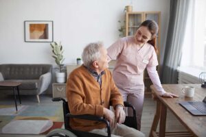 Older adult arranging family photos, a lamp, and personal keepsakes in a bright assisted living apartment.